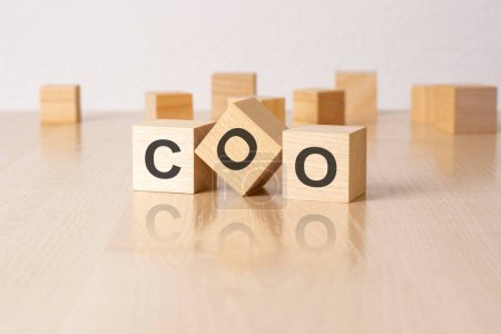 COO - an abbreviation of wooden blocks with letters on a brown background. reflection mirrored surface of the table