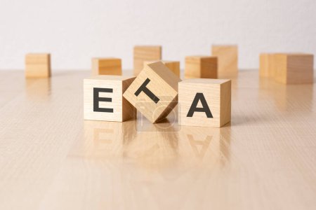 ETA - eine Abkürzung für Holzklötze mit Buchstaben auf grauem Hintergrund. Bildunterschrift auf der Spiegelfläche des Tisches.