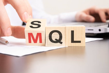 SQL- oder MQL-Symbol. Geschäftsmann dreht Würfel und ändert Wörter 'MQL Marketing Qualified Lead' in 'SQL Sales Qualified Lead'.
