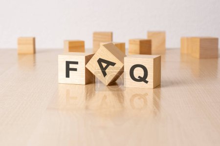 FAQ - an abbreviation of wooden blocks with letters on a gray background. reflection caption on the mirrored surface of the table.