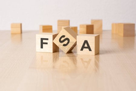 FSA - eine Abkürzung für Holzklötze mit Buchstaben auf grauem Hintergrund. Bildunterschrift auf der Spiegelfläche des Tisches.