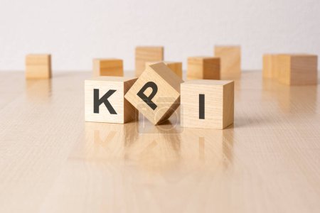 kpi - an abbreviation of wooden blocks with letters on a gray background. reflection caption on the mirrored surface of the table.