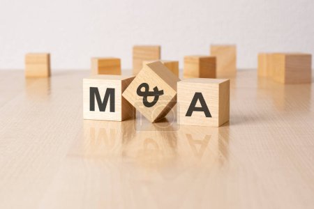 m and a - an abbreviation of wooden blocks with letters on a gray background. reflection caption on the mirrored surface of the table.
