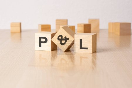 P and L - an abbreviation of wooden blocks with letters on a gray background. reflection caption on the mirrored surface of the table.