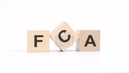 Wort FCA - Financial Conduct Authority - aus Holzbausteinen, weißer Hintergrund.