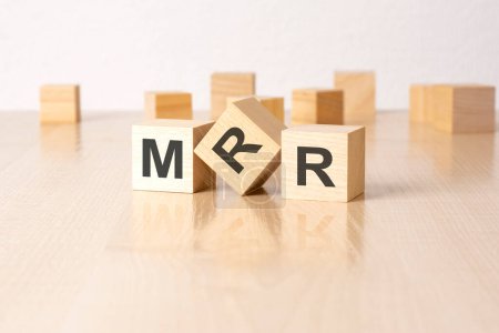mrr - eine Abkürzung für Holzklötze mit Buchstaben auf grauem Hintergrund. Bildunterschrift auf der Spiegelfläche des Tisches.
