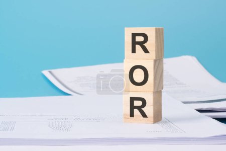 Holzwürfel mit Text ROR - Rate Of Return - auf Geschäftsdokument.