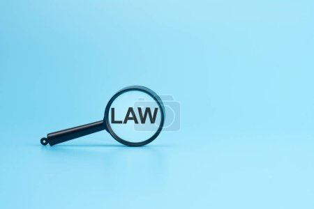 LAW text on magnifier on blue background, business concept
