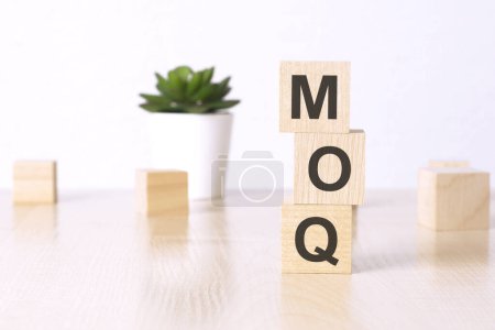 MOQ - Mindestbestellmenge - Text auf Holzwürfeln auf weißem Hintergrund.