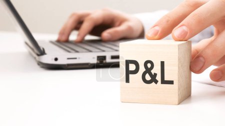 man holding wooden cube witt letters P and L in the background a laptop on a white office table background