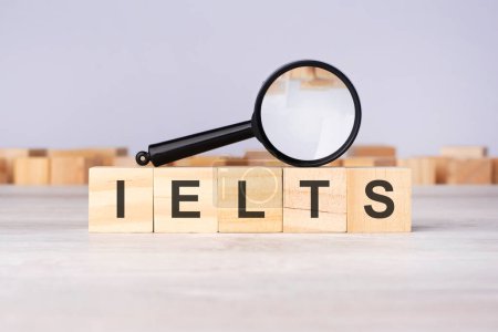 Holzblöcke mit einer Lupe Text: IELTS - International English Language Testing System