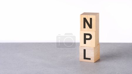 Großaufnahme von Holzblöcken mit dem Wort NPL - Non Performing Loans - auf grauem Tisch