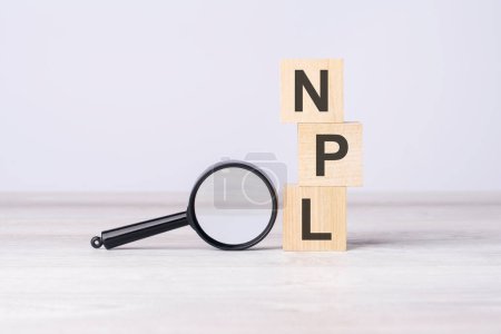 NPL - or Non Performing Loans concept. text on wooden cubes under a magnifying glass.