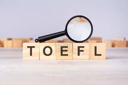 Holzblöcke mit einer Lupe Text: TOEFL - Test Of English As A Foreign Language