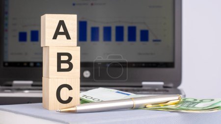 primer plano de los bloques de madera con la palabra ABC y billetes en el fondo de un ordenador portátil, concepto de negocio