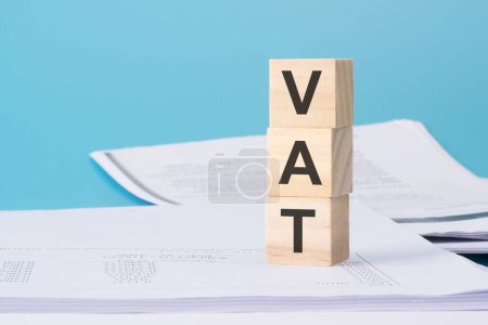 wooden cubes with text VAT - Value Added Tax - on business document.