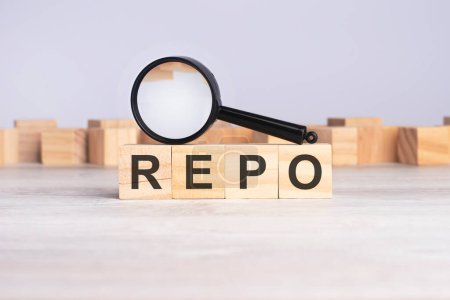magnifying glass and wooden blocks with the text: REPO. can be used for business, marketing and education concept
