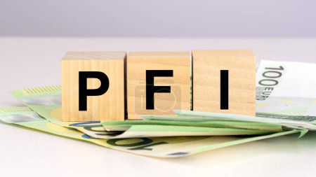 Photo for PFI - short for Private Finance Initiative. text on wood cubes with euro bills. front view - Royalty Free Image