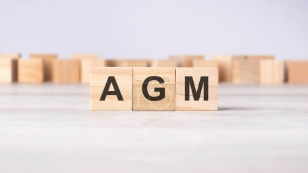 AGM - acronym concept written on wooden cubes or blocks on a light grey background