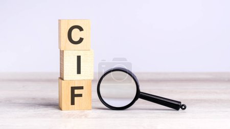 cif - cost insurance and freight - text wooden cube blocks and magnifying glass on table. business concept.
