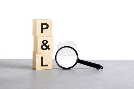 PL - profit and loss - text wooden cube blocks and magnifying glass on gray table, business concept
