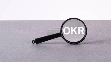 OKR text through a magnifying glass written on a light background.