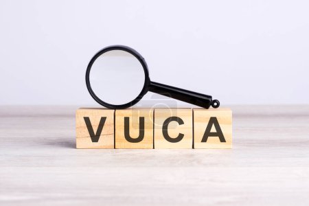 Lupe und Holzbausteine mit dem Text: VUCA. kann für Geschäfts-, Marketing- und Bildungskonzepte verwendet werden