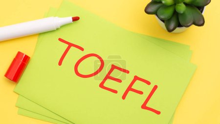 green card with text TOEFL on a yellow background with red marker