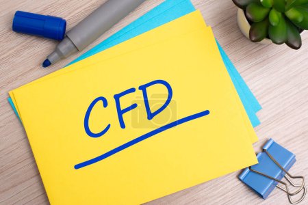cfd - Contracts For Difference - text on yellow paper on light wooden background with stationery.