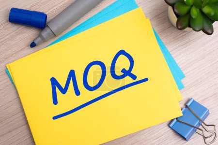 Foto de MOQ - cantidad mínima de pedido - concepto de texto acrónimo con marcador azul en la tarjeta amarilla - Imagen libre de derechos