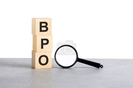 bpo - Business Process Outsourcing - Text Holzwürfelblöcke und Lupe auf grauem Tisch, Geschäftskonzept