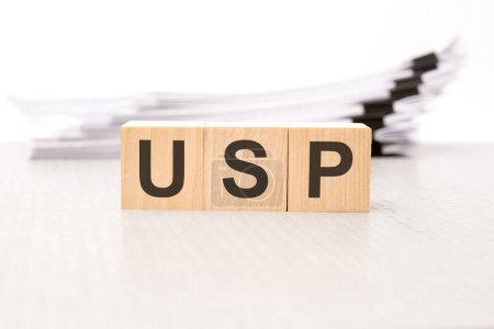 text usp - Unique Selling Proposition - on wooden blocks. the background is a business papers. finance concept. white background