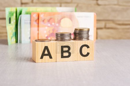 Geschäftskonzept. Auf einer grauen Fläche stehen Dollars und Holzblöcke mit der Aufschrift - ABC - kurz für Always Be Closing