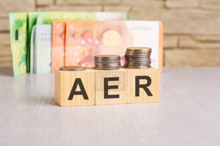 Business concept. On a grey surface, dollars and wooden blocs with the inscription - AER - short for Annual Equivalent Rate