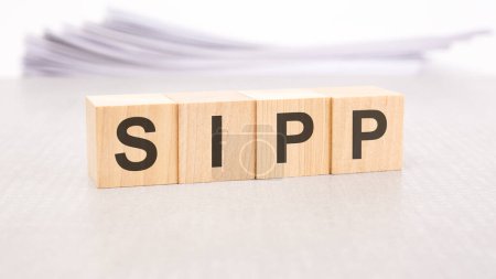 sipp text written on wood blocks, stack of white sheets in the background