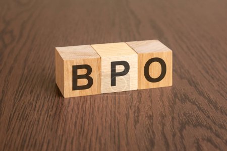 BPO - Business Process Outsourcing - Abkürzung für Holzwürfel auf dunklem Holzgrund