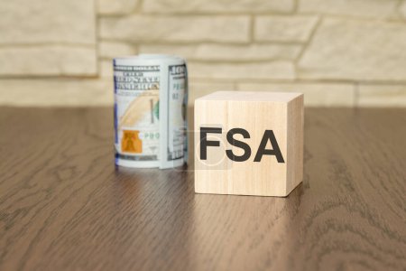 Holzblock mit Text FSA auf dunklem Hintergrund - flexibles Ausgabenkonto und Geschäftskonzept