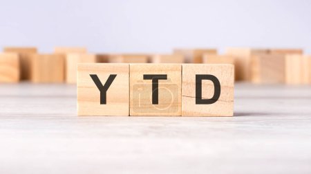 YTD - concept d'acronyme - cumulatif - écrit sur des cubes ou des blocs de bois sur un fond gris clair