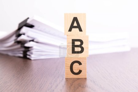 cubos de madera con letras ABC dispuestos en una pirámide vertical, apilar papel blanco sobre fondo