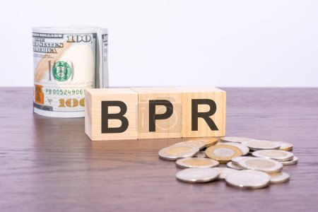 Draufsicht auf Holzblöcke mit Text BPR (Business Process Reengineering) über US-Dollar-Banknoten auf braunem Hintergrund. Konzept der Verlässlichkeit