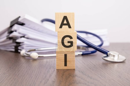 Foto de Texto AGI escrito en bloques de madera cerca de un estetoscopio sobre un fondo de papel, concepto médico - Imagen libre de derechos