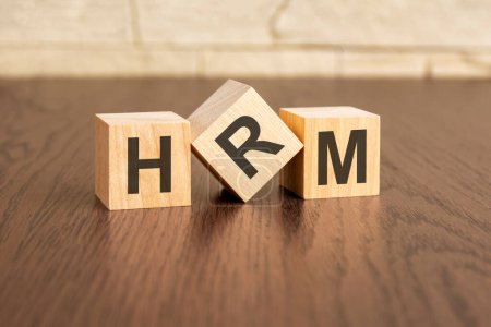 human resource management concept with symbols hrm on wooden blocks, dark wooden background