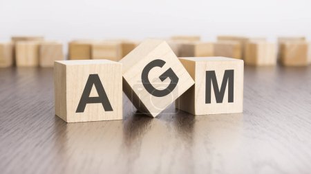 wooden blocks with text AGM on brown table