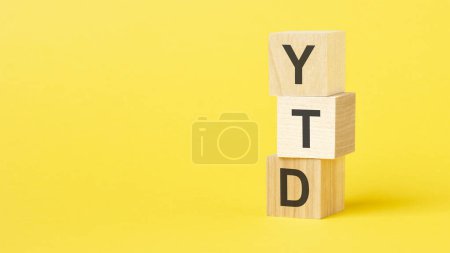 Holzwürfel mit Text YTD - kurz für Jahr bis heute. gelber Hintergrund