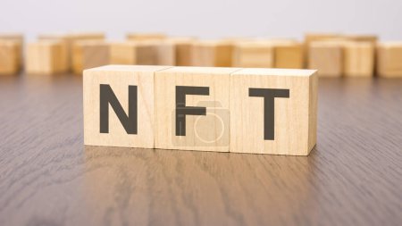 NFT text on wooden cubes - acronym short for Non Fungible Token. wooden background. foreground