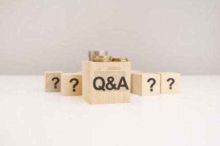 Photo for Q and A concept. wooden block with QA - Question and Answer - symbol and question marks with coins on gray background - Royalty Free Image