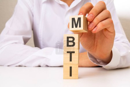 businessman holding with wooden blocks with MBTI text. Psychological and personality test concept, Personality typology. Psychology test for human types. MBTI - Myers-Briggs Type Indicator