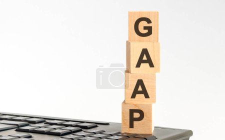word GAAP with wooden cubes on keyboard, light white background