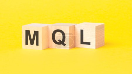 texto MQL - comercialización de plomo calificado - escrito en cubos de madera sobre fondo amarillo