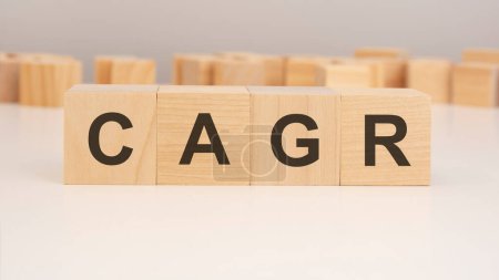 short word english letters with text - CAGR - on a small wooden cubes with white background. copy space concept. selection focus